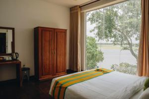a bedroom with a bed and a large window at Yala Oga Reach Hotel in Tissamaharama