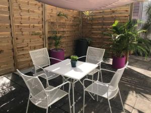 une table et des chaises blanches sur une terrasse avec des plantes en pot dans l'établissement Studio cosy rez de jardin à 10 mn des plages, à Baie-Mahault