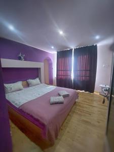 um quarto com uma cama roxa com duas toalhas em Стаи за гости Върбите em Sapareva Banya