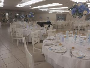 Partenone Resort Hotel في رياس مارينا: قاعة احتفالات بطاولات بيضاء وكراسي بيضاء