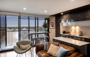 a living room with a couch and a kitchen at The Retreat Adelaide in Adelaide
