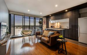 a living room with a couch and a kitchen at The Retreat Adelaide in Adelaide