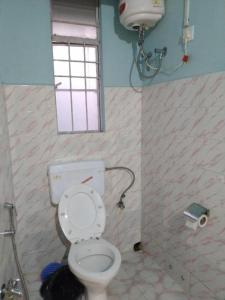 a bathroom with a toilet and a window at Stay Inn Pumpkin Guest House in Shillong
