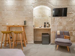ein Zimmer mit zwei Stühlen, einem Tisch und einem Fernseher in der Unterkunft Hydria Rooms in Matera