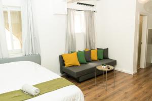 a bedroom with a couch with yellow and green pillows at kotel apartment in Jerusalem