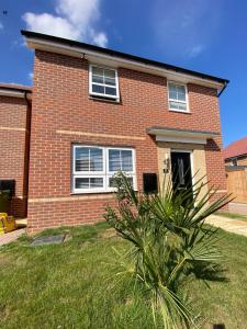 a brick house with a palm tree in front of it at Single bedroom - Hampton Water, Peterborough in Peterborough