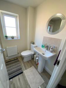 a bathroom with a sink and a toilet and a mirror at Single bedroom - Hampton Water, Peterborough in Peterborough