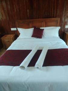 a large bed with white sheets and red pillows at Don's River Valley Jungle Resort in Maraiyūr