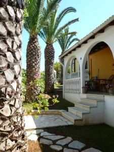 a house with two palm trees in the yard at Athina Apartments in Arillas