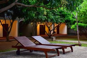 zwei Picknicktische neben einem Gebäude mit Bäumen in der Unterkunft Tropicara Resort in Sigiriya