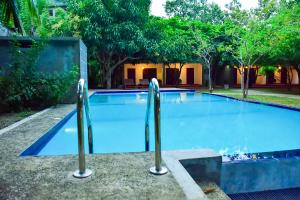 a large swimming pool with two metal bars in it at Tropicara Resort in Sigiriya