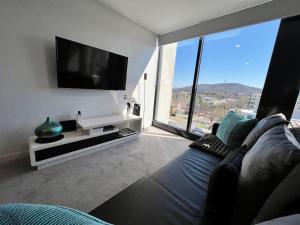 ein Wohnzimmer mit einem Sofa und einem Flachbild-TV in der Unterkunft Midnight Luxe 1BR Executive Apartment in the heart of Braddon Views L7 Pool Sauna Gym Secure Parking Wifi Wine in Canberra