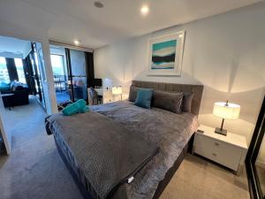 a bedroom with a large bed with blue pillows at Midnight Luxe 1BR Executive Apartment in the heart of Braddon Views L7 Pool Sauna Gym Secure Parking Wifi Wine in Canberra