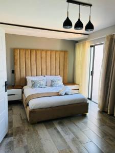 Schlafzimmer mit einem großen Bett mit einem Kopfteil aus Holz in der Unterkunft Maison De luxe in Thohoyandou