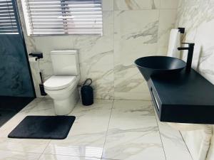 ein Bad mit einem schwarzen Waschbecken und einem WC in der Unterkunft Maison De luxe in Thohoyandou