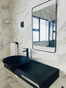 ein Bad mit einem schwarzen Waschbecken und einem Spiegel in der Unterkunft Maison De luxe in Thohoyandou