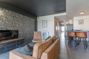 - un salon avec un canapé et une télévision dans l'établissement Les Figuiers - Appartement 2 Chambres avec Sauna à Andenne, à Andenne