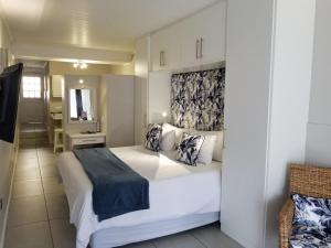 a bedroom with a large white bed and a mirror at Riviera Hotel Hartenbos in Mossel Bay