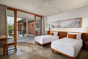 a bedroom with two beds and a desk and a table at Villa Uma Santai by Nakula in Canggu
