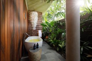 a bathroom with a bath tub and some plants at Villa Uma Santai by Nakula in Canggu