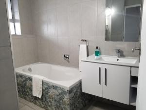 a white bathroom with a tub and a sink at Riviera Hotel Hartenbos in Mossel Bay
