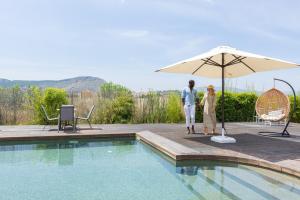 a man and woman standing under an umbrella near a swimming pool at Palacio del Sol Luxury Apartments in Nafplio