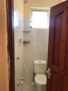 a bathroom with a toilet and a window at Lux Suites Mwembeni Flats Mtwapa in Mtwapa
