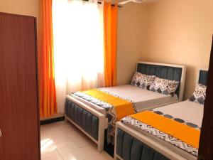two beds in a room with an orange curtain at Lux Suites Mwembeni Flats Mtwapa in Mtwapa +6 photos