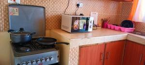 a kitchen with a stove and a microwave at Lux Suites Mwembeni Flats Mtwapa in Mtwapa
