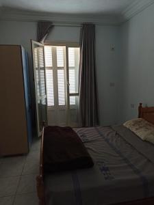 Schlafzimmer mit einem Bett, einem Fenster und einer Tür in der Unterkunft appartamenti Oueslati in Houmt Souk