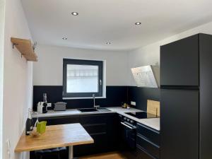 a kitchen with a black refrigerator and a wooden table at Haus 11 in Oberkirch