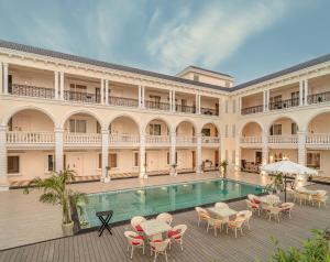 a large building with a pool and tables and chairs at Rudra Imperial Resort in Sītāpur