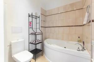 a bathroom with a white tub and a toilet and a sink at Lenka's cozy Red studio + Lenka's cozy Gold apartment in Prague +19 photos