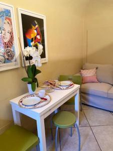 una mesa con platos y flores y un sofá en Civico 8 en Rivarolo Canavese