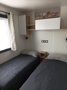 鲁西隆地区卡内Mobil home moderne neuf et ultra équipé de 6 à 8 couchages的一间带窗户的小房间里有两张床 更多33张照片
