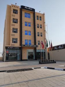 een groot gebouw met vlaggen ervoor bij العلي للشقق المخدومة Alalihotel in Hafr Al Baten