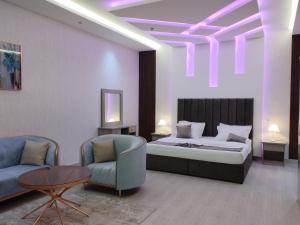 1 dormitorio con 1 cama, 2 sillas y mesa en العلي للشقق المخدومة Alalihotel en Hafr Al Batin