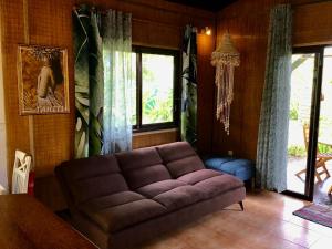 sala de estar con sofá marrón y ventanas en Faré Anaiti Moorea en Iumaru