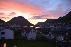 a view of a town at sunset with mountains at Cozy cottage in Klaksvík