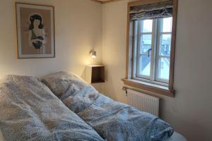 a bed with a blanket in a room with a window at Cozy cottage in Klaksvík