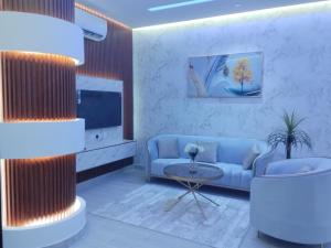 a living room with a blue couch and a tv at العلي للشقق المخدومة Alali Serviced Apartments in Hafr Al-Batin
