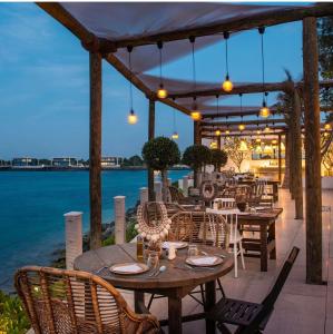 a patio with tables and chairs and the water at Nurai Losin in Abu Dhabi
