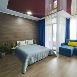 een slaapkamer met een bed en een blauwe stoel bij Смарт квартира в ЖК Комфорт Таун in Kiev