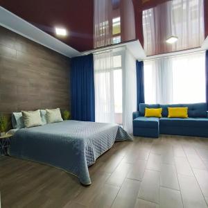 een slaapkamer met een bed, een bank en ramen bij Смарт квартира в ЖК Комфорт Таун in Kiev