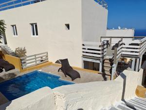 a villa with a swimming pool and two chairs at Anemomilos Villa in Firostefani