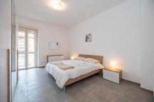 a white bedroom with a large bed and two lamps at Appartamento Esclusivo - Zona Metro Massaua-Marche Torino in Turin