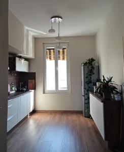 une cuisine avec des placards blancs et une grande fenêtre dans l'établissement La Maison de Jeanne, à Narbonne