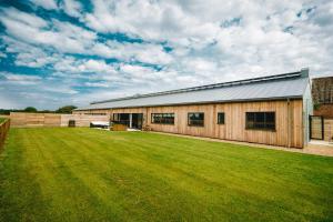 a wooden building with a large grass yard at Sandy Barn *BRAND NEW* Barn Conversion in Tunstead