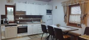 eine Küche mit weißen Schränken und einem Tisch mit Stühlen in der Unterkunft Wellness Chata Horbek in Vyšné Ružbachy