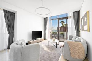 StoneTree - Anwa By Omniyat 2BR - Luxury Apartment في دبي: غرفة معيشة مع كرسيين وتلفزيون